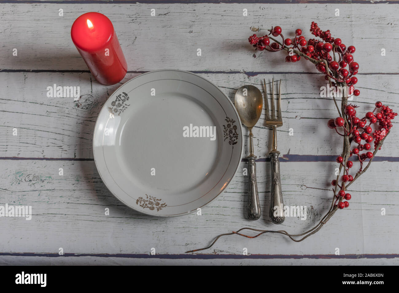 Christmas table with antique silver cutlery, red candle on a white wooden background Stock Photo