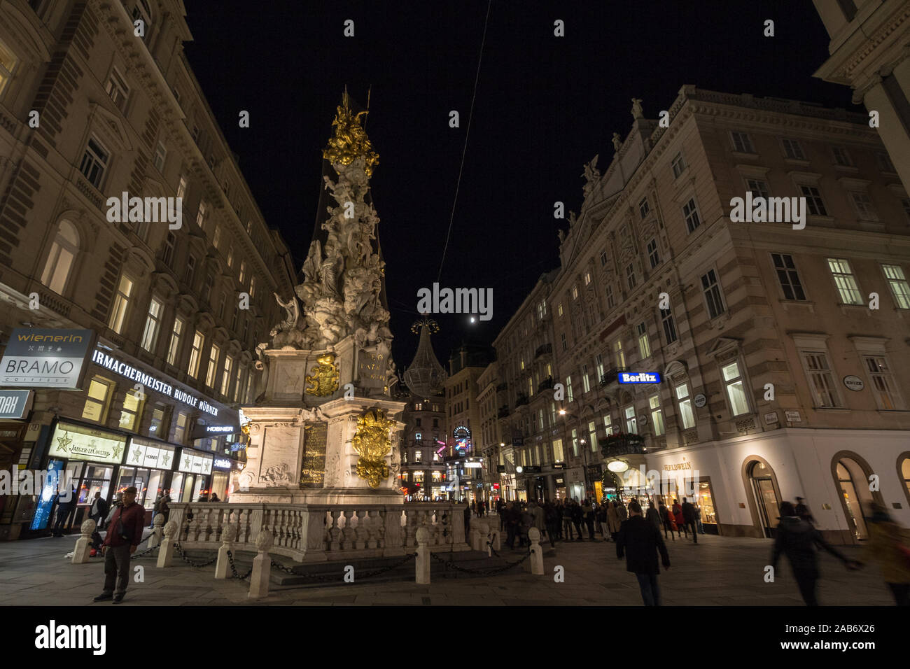 VIENNA, AUSTRIA - NOVEMBER 6, 2019: Wiener Pestsaule, also called the Plague Column, on Graben street, at nights, with pedestrians passing by. It is a Stock Photo