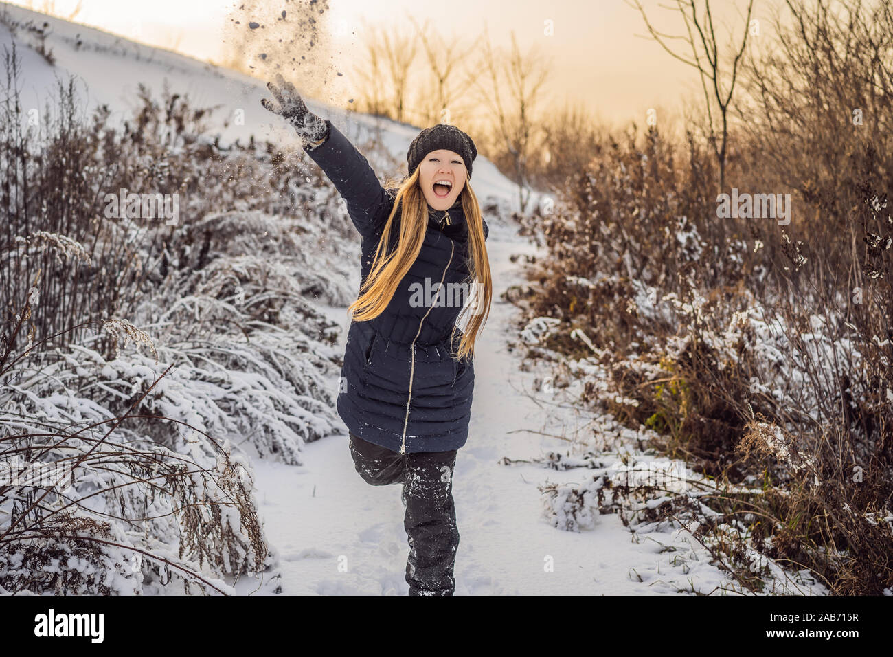 winter girl throwing snowball at camera smiling happy having fun ...