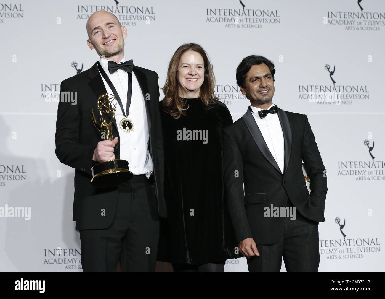 New York, United States. 25th Nov, 2019. British film maker James Watkins (L), Indian actor Nawazuddin Siddiqui and British producer Dixie Linder (R) stand in the press room with the award for 'Drama Series' for 'McMafia' at the 47th International Emmy Awards at the New York Hilton in New York City on November 25, 2019. Photo by John Angelillo/UPI Credit: UPI/Alamy Live News Stock Photo