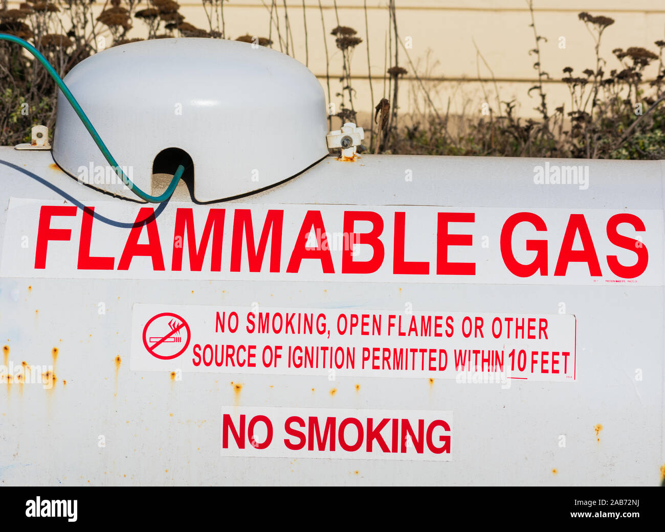 Flammable gas warning on above ground large propane tank. Rust or corrosion on the white propane tank surface. Stock Photo