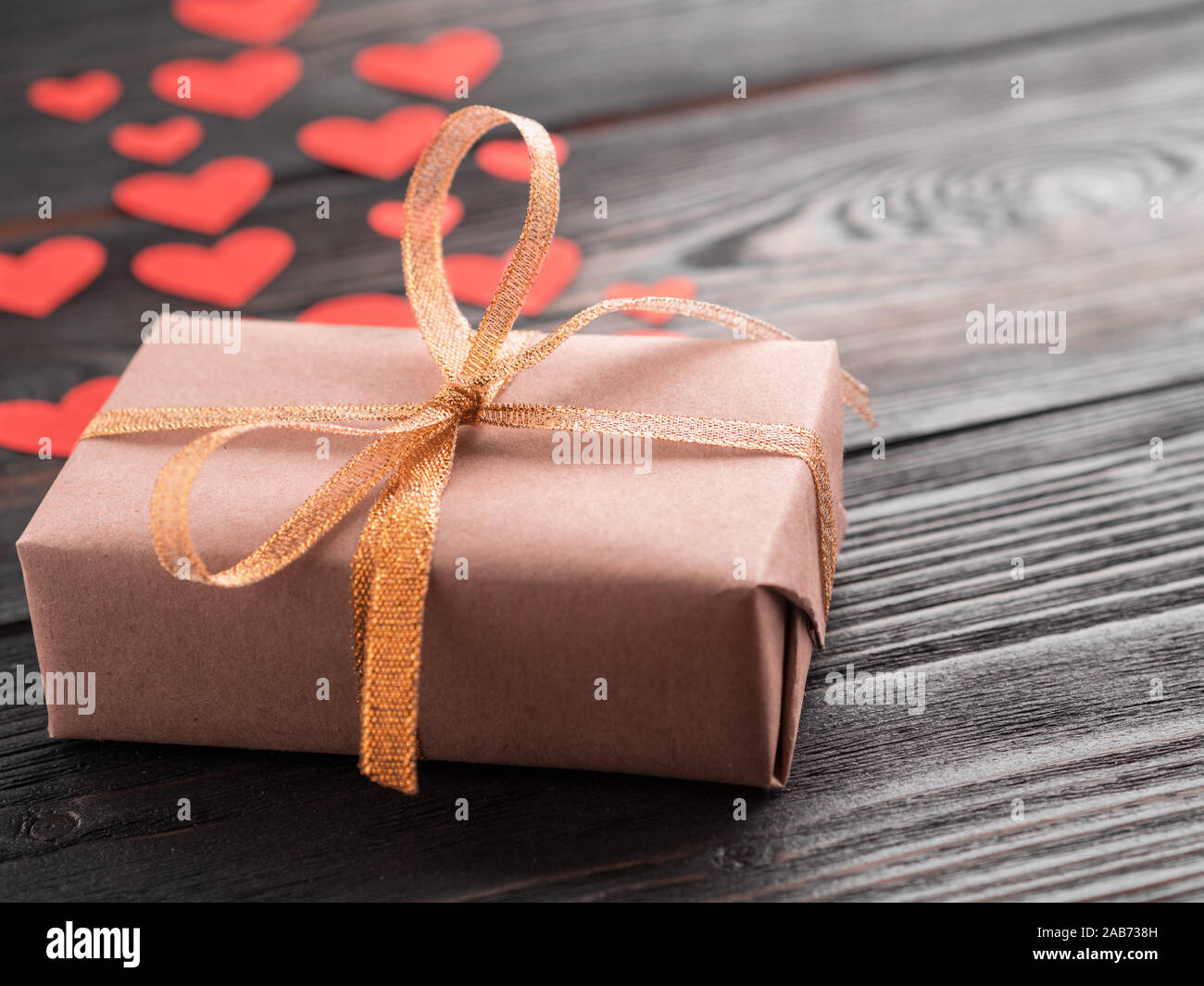 gift box with ribbon and lots of little red hearts on wooden texture ...