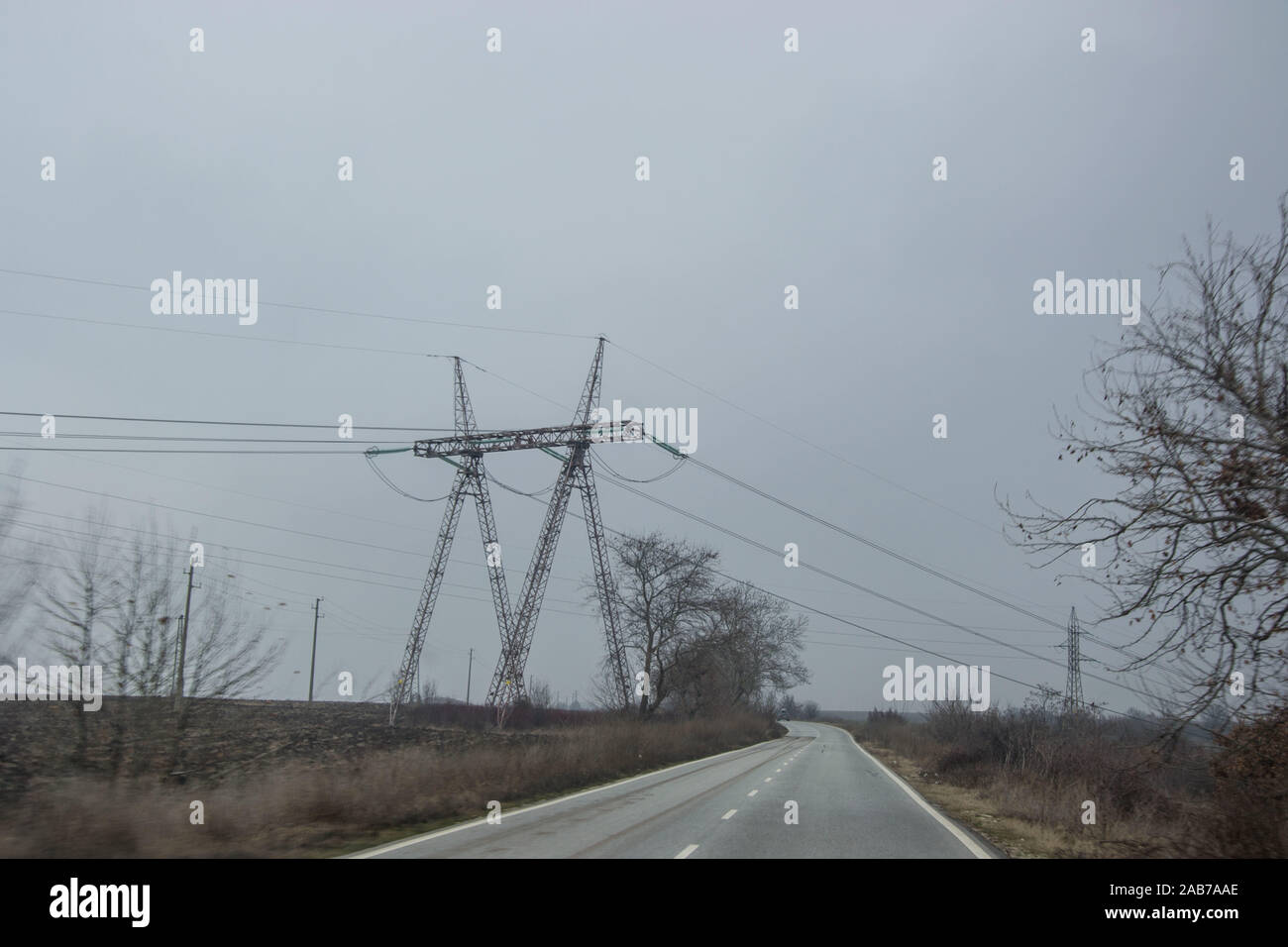 Misty car road in Bulgaria with electricity pylons with wires ...