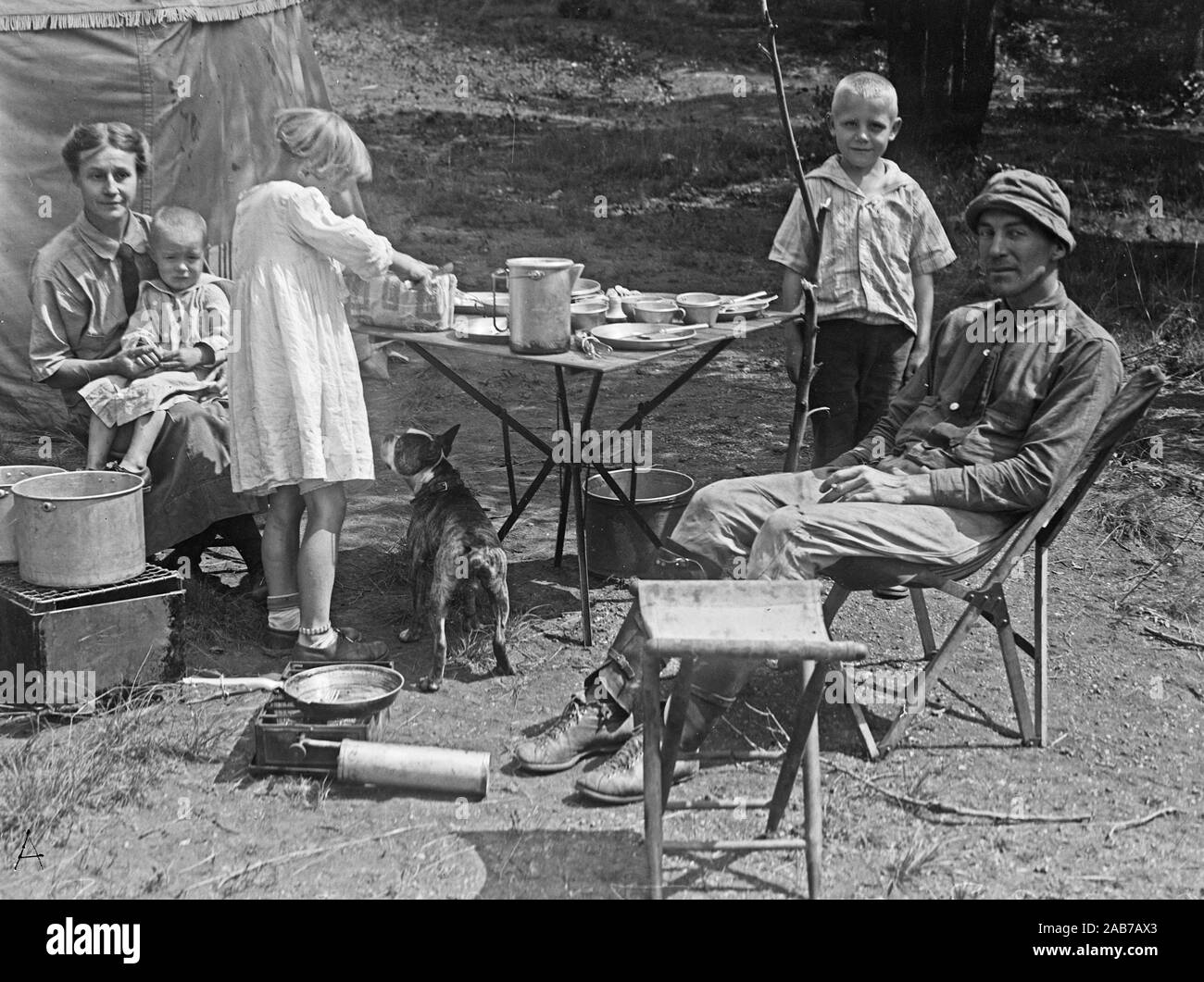 A family camping and eating outside next to their car camper ca. 1915-1923 Stock Photo
