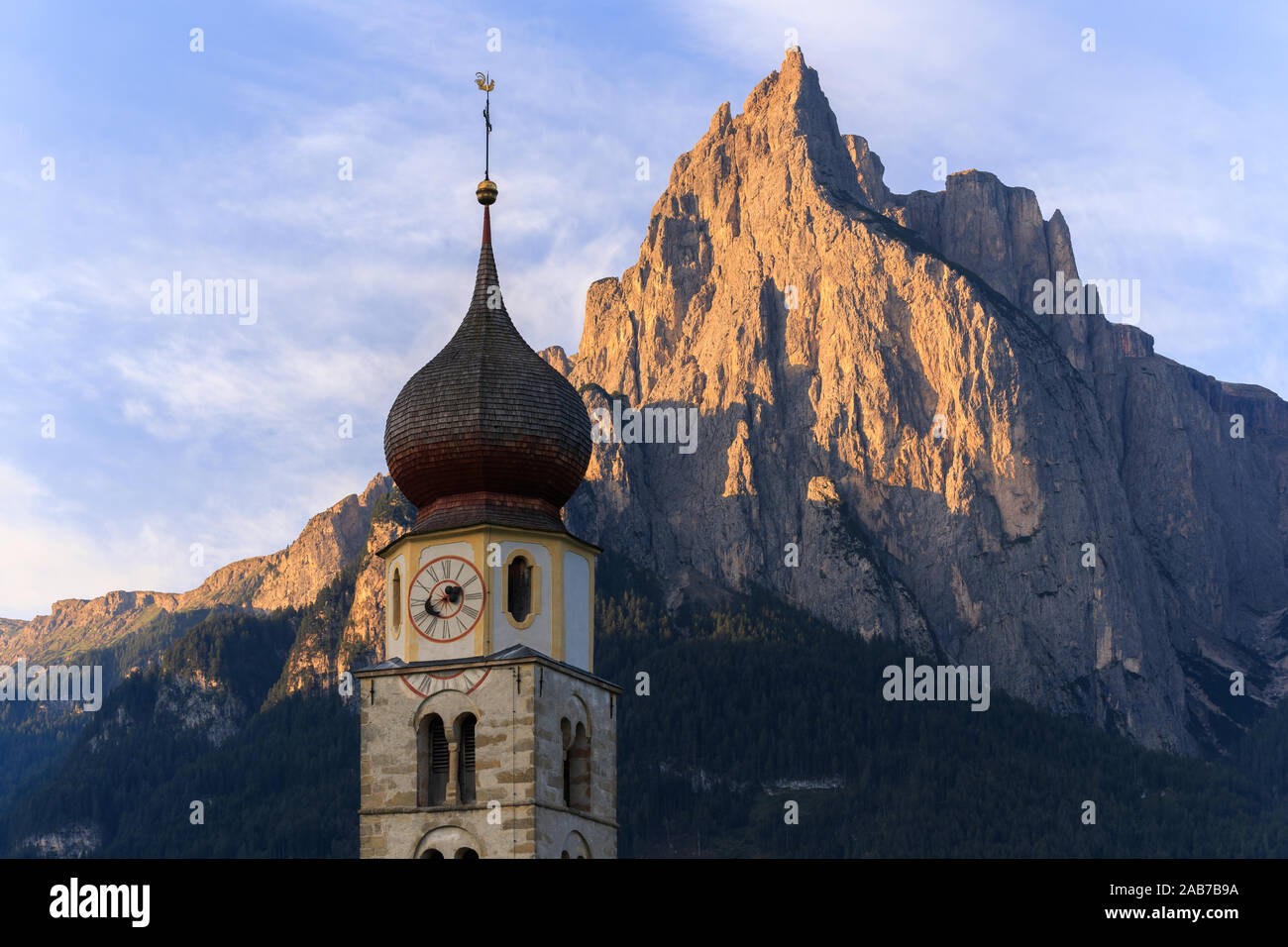 Sunrise landscapes of Church St. Valentin on grassy hilltop with view of rugged peaks of Mountain Schlern with alpenglow in background in the valley o Stock Photo
