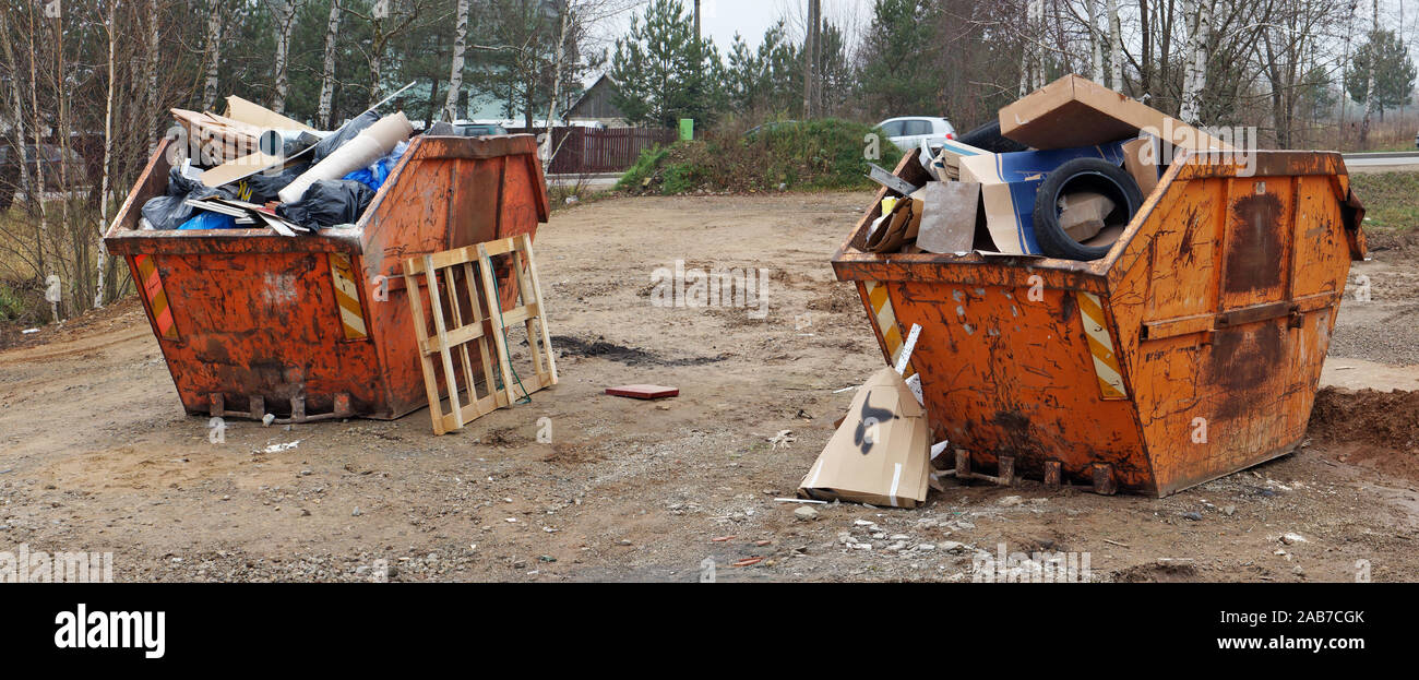 Crushed rusty orange color garbage containers filled with construction ...