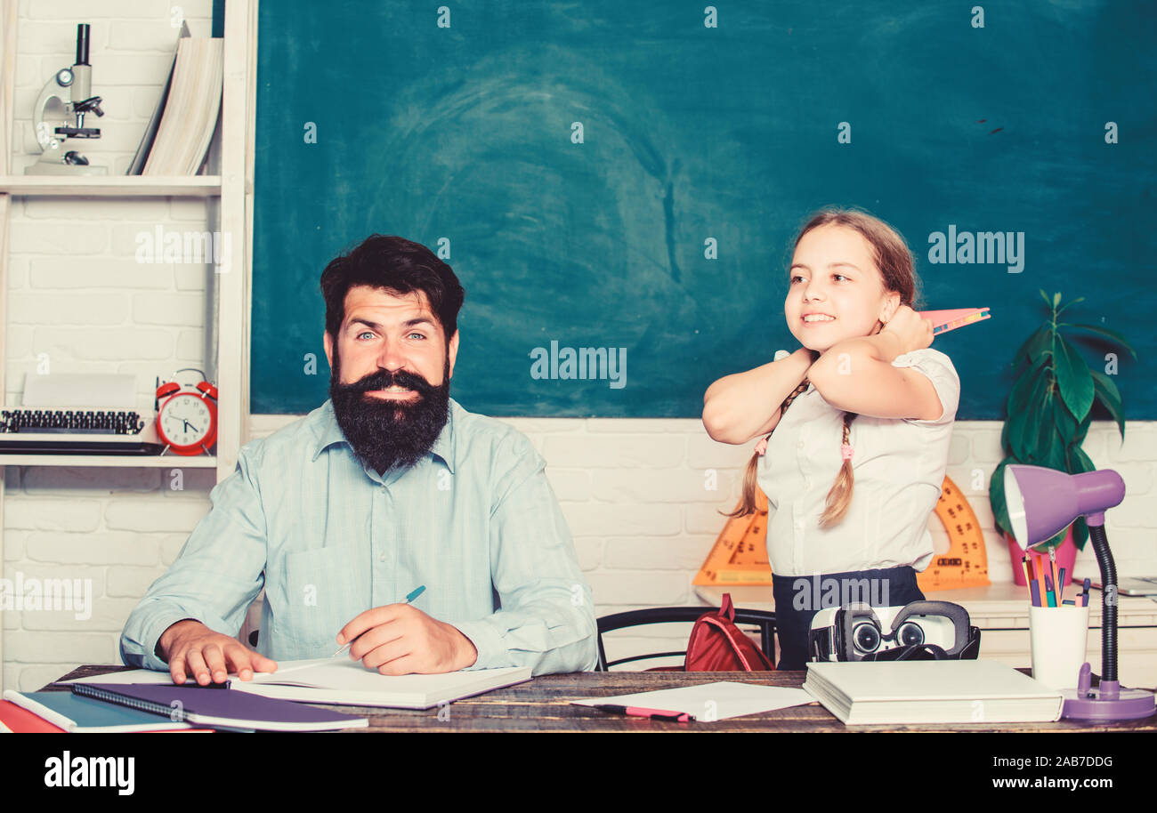 It is unbelievable. daughter study with father. Teachers day. knowledge day. Home schooling. back to school. Private teaching. private lesson. small girl child with bearded teacher man in classroom. Stock Photo