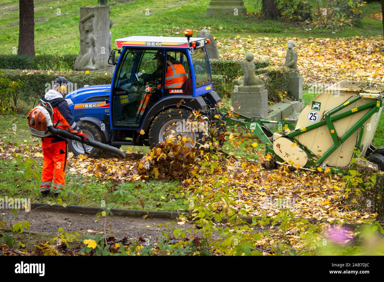 worker with a backpack leaf blower and mechanical picking up of leaves in a public park in the city of Wetter, North Rhine-Westphalia, Germany.  Arbei Stock Photo