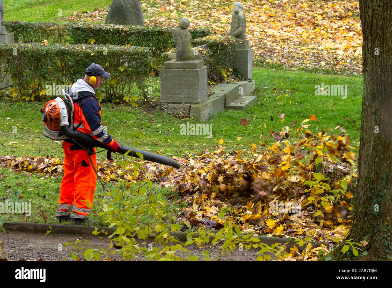 worker with a backpack leaf blower in a public park in the city of Wetter, North Rhine-Westphalia, Germany.  Arbeiter mit einem Laubblaeser in einem o Stock Photo