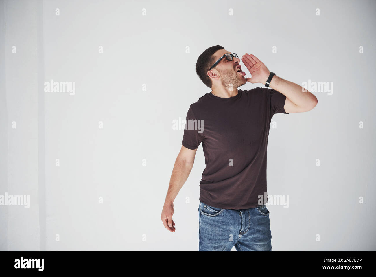 Emotional man in casual clothes loudly screams as if someone is calling. His feelings are overwhelming Stock Photo