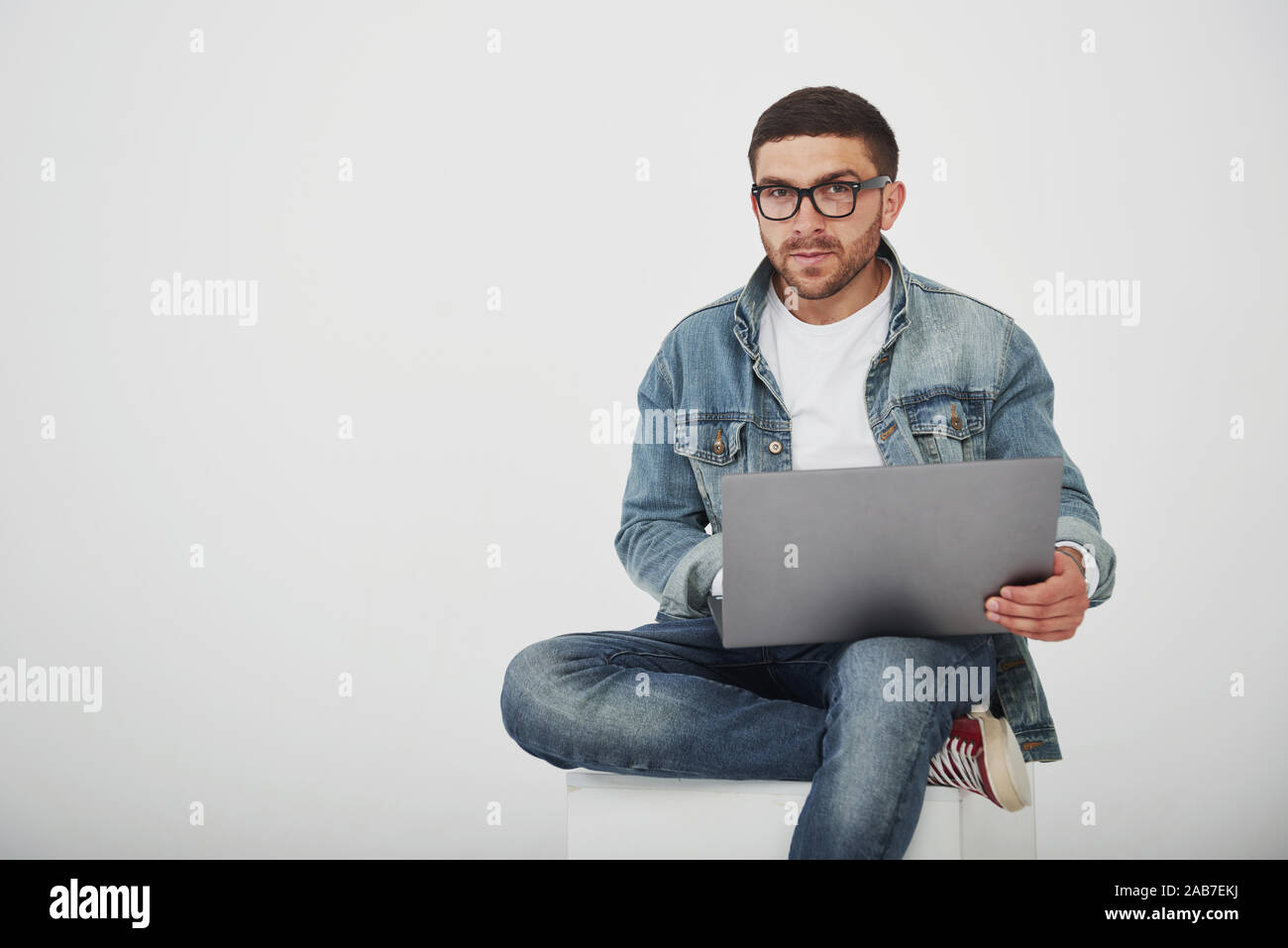 Handsome young man with laptop and check his timetable on white background Stock Photo