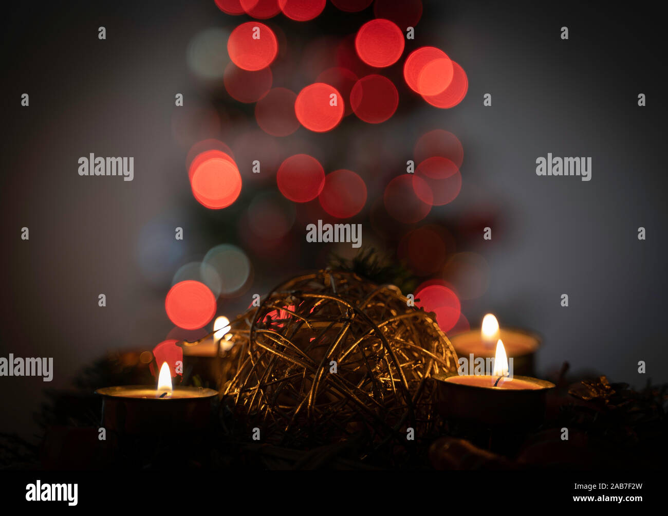 Advent or Christmas wreath with four burning candles. Close up image. Out of focus christmas tree in the background. Bokeh of christmas lights. Stock Photo