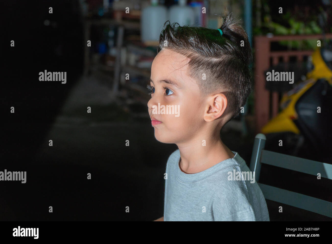 A Cute Boy With A Spiky Hairstyle Sitting In The Dark Stock Photo