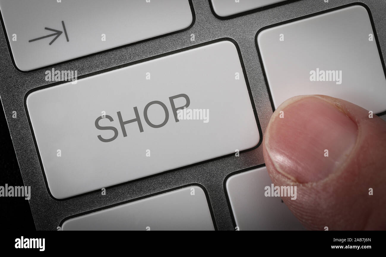 A man pressing a key on a computer keyboard with the word shop. Online shopping concept image. Stock Photo