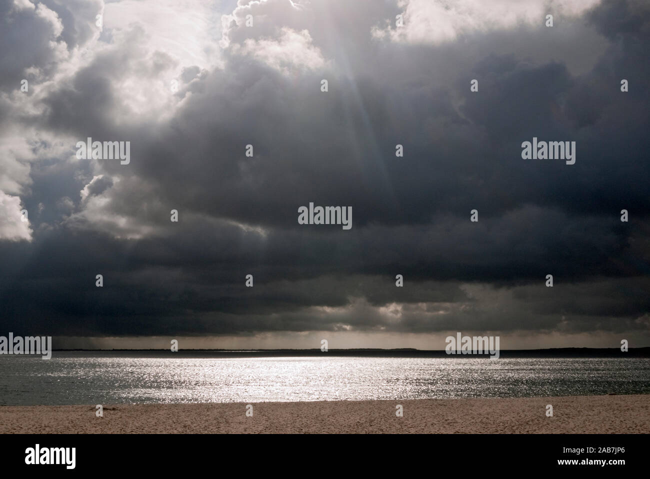 Sonnenlicht durchbricht dunkle Regenwolken am Strand bei Hoernum Stock Photo
