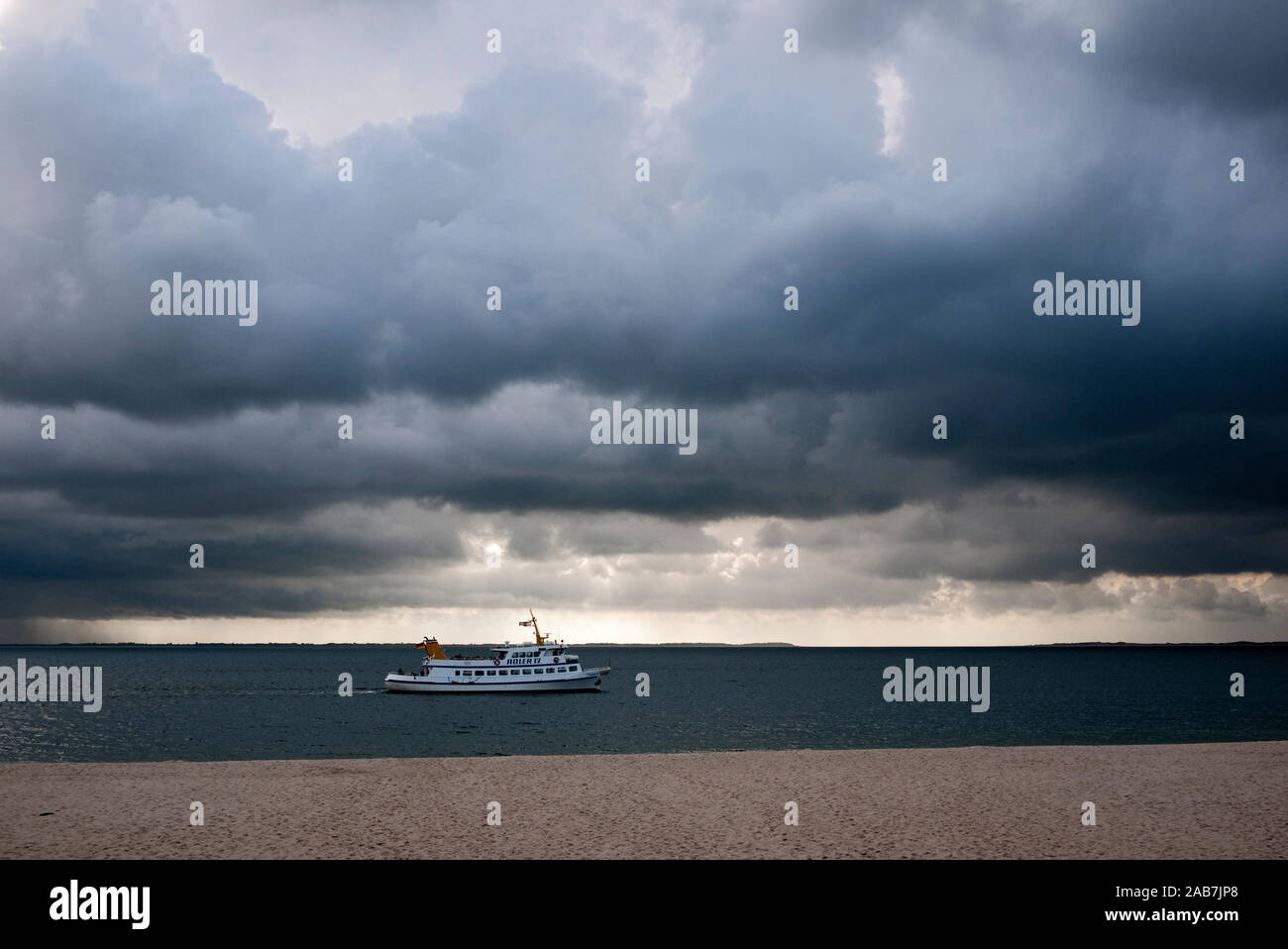 Ausflugsschiff  vor dem Strand bei Hoernum unter dunklen Regenwolken Stock Photo