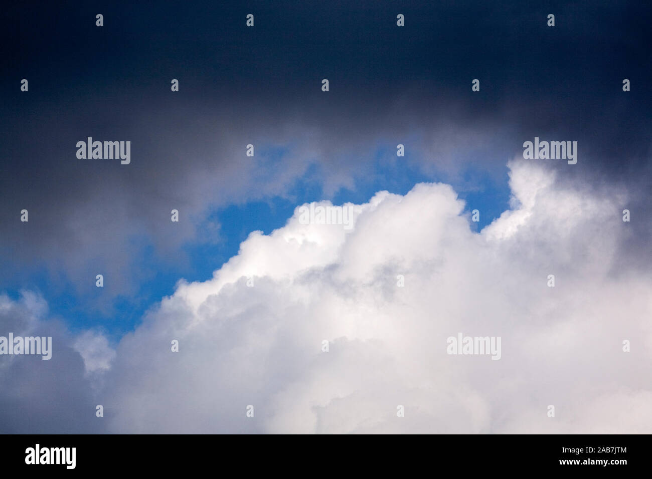 Dichte weisse und dunkelgraue Quellwolken vor blauem Himmel Stock Photo