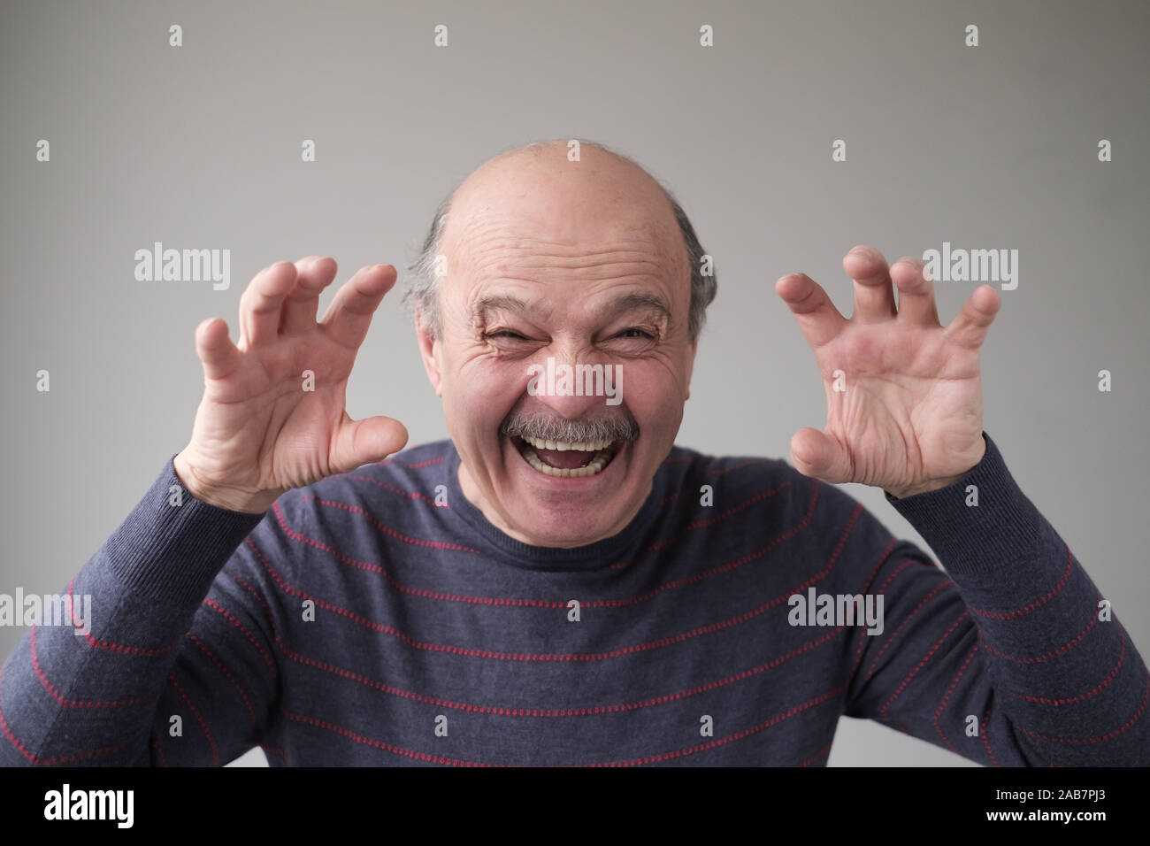 Senior hispanic man with creepy face grimacing to scare you. Studio ...