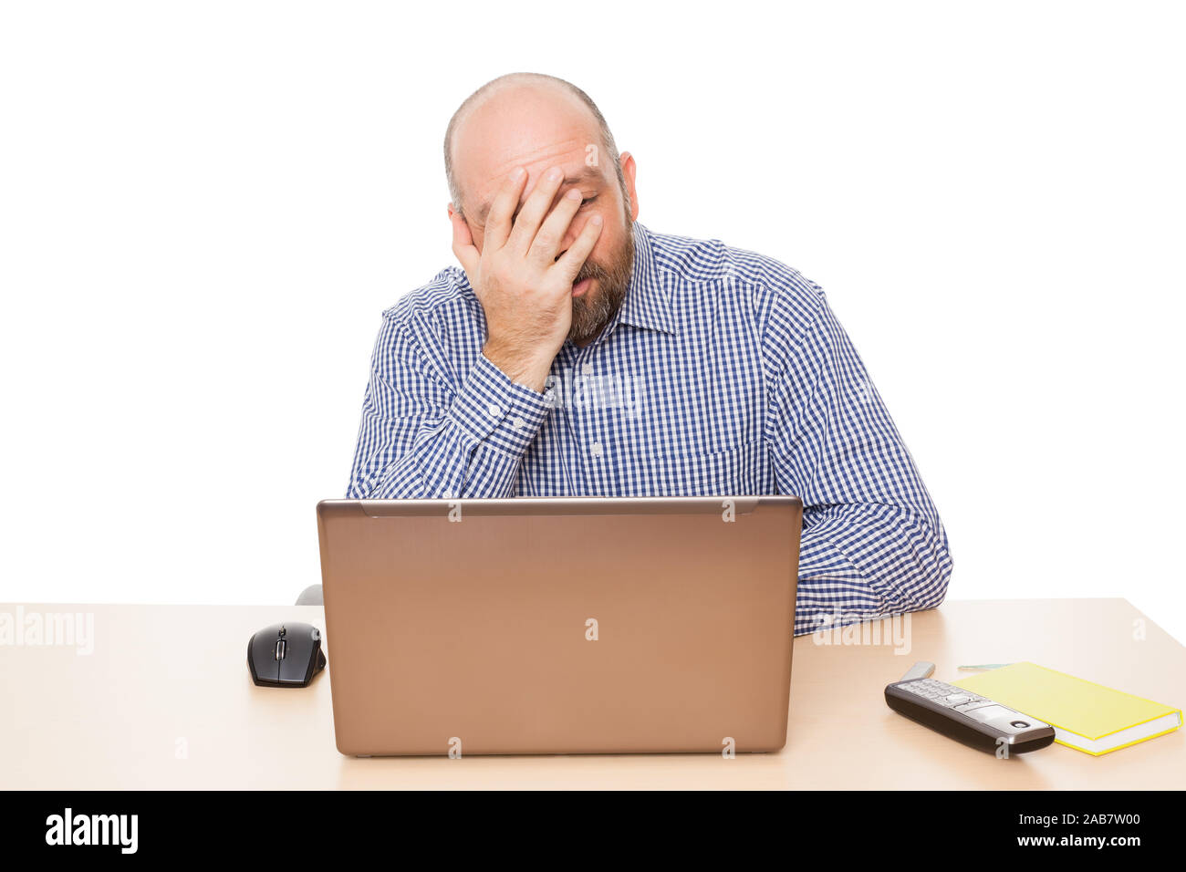 Ein deprimierter Geschaeftsmann an seinem Schreibtisch vor weissem Hintergrund Stock Photo