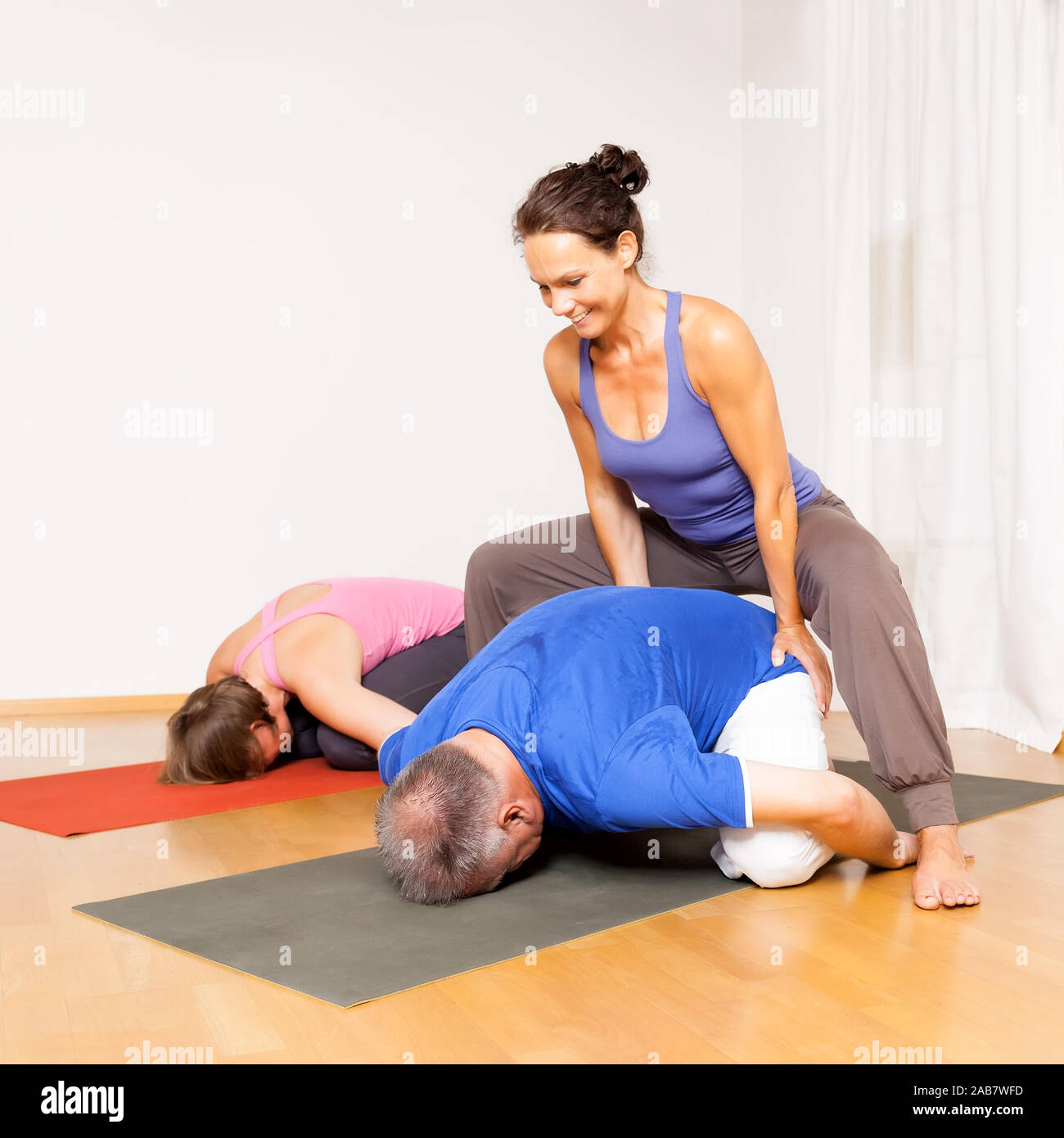 Maenner und Frauen, die Yoga-Uebungen durchfuehren Stock Photo