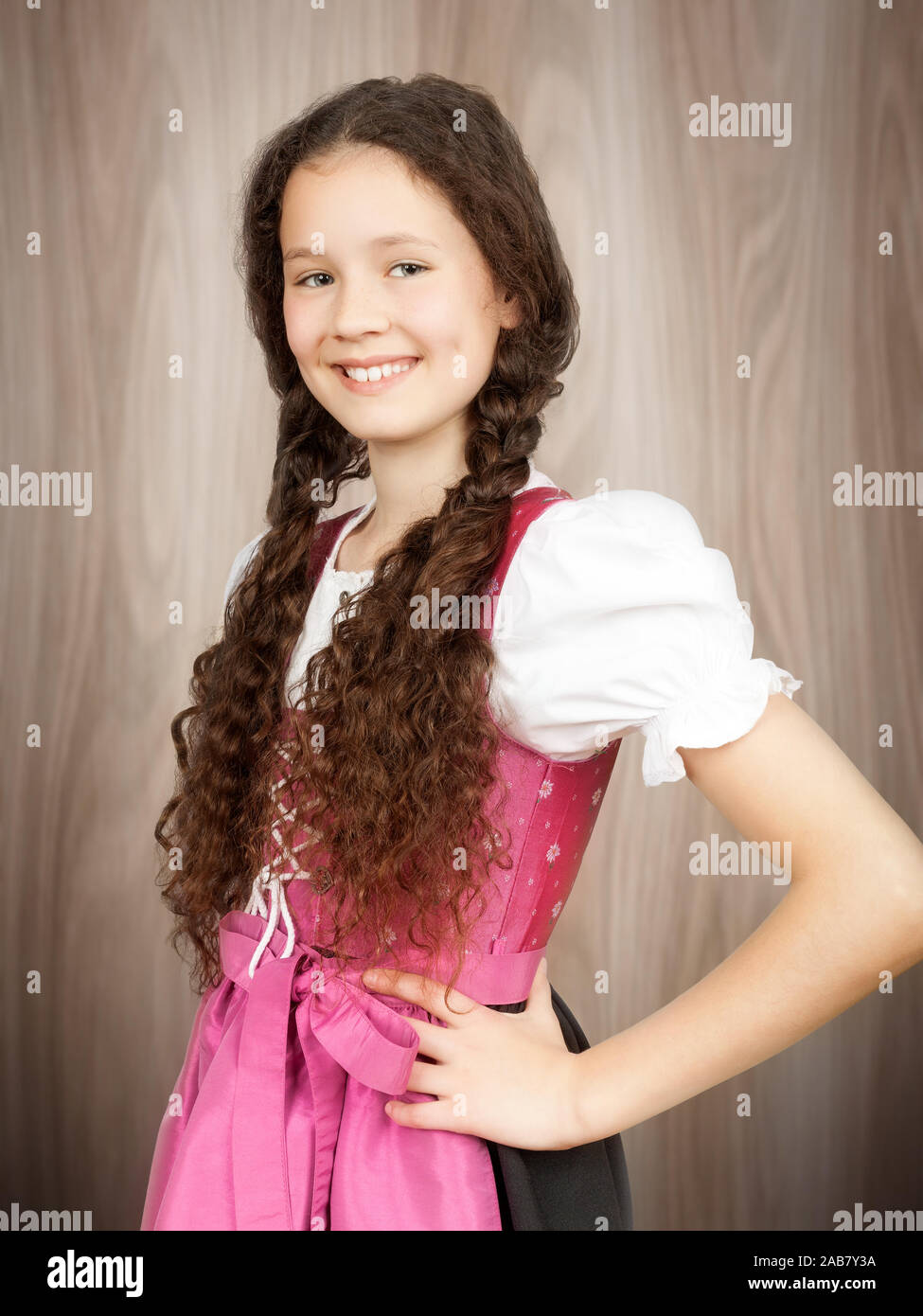 Ein suesses bayerisches Maedchen im rosa Dirndl vor hoelzernem Hintergrund Stock Photo