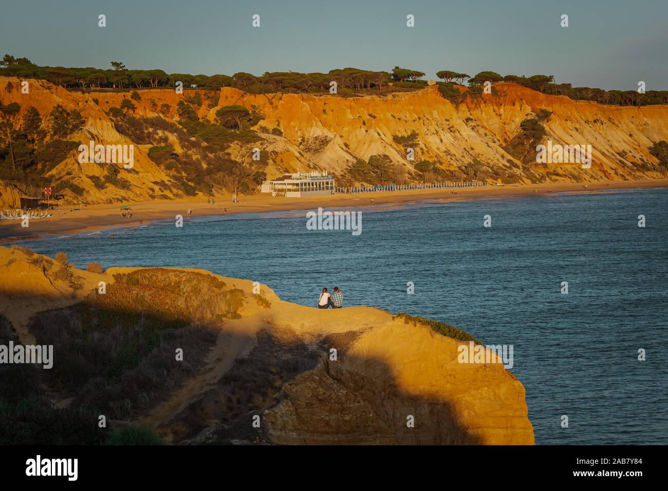 Olhos D'Agua, Portugal - October 04 2019: A young couple share a romantic moment with a view of Falesia Beach at sunset Stock Photo