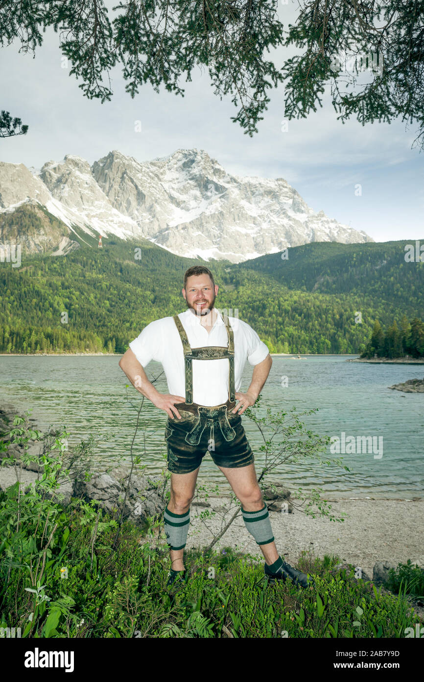 Ein junger netter Mann in bayerischer Tracht vor einer Bergkulisse Stock Photo