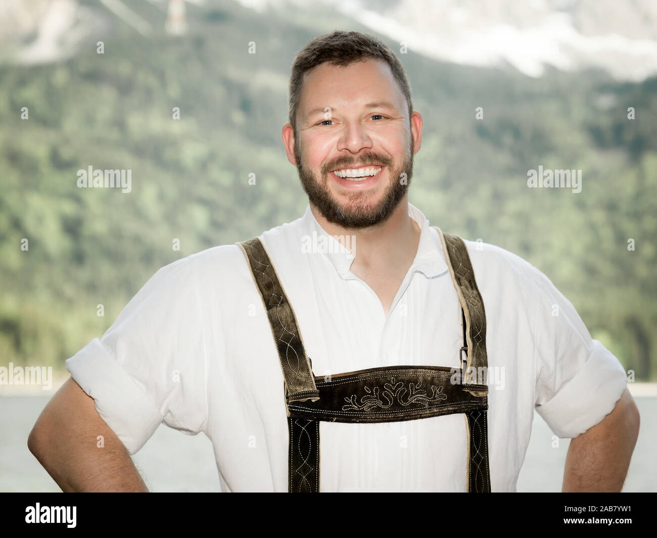 Ein junger netter Mann in bayerischer Tracht vor einer Bergkulisse Stock Photo
