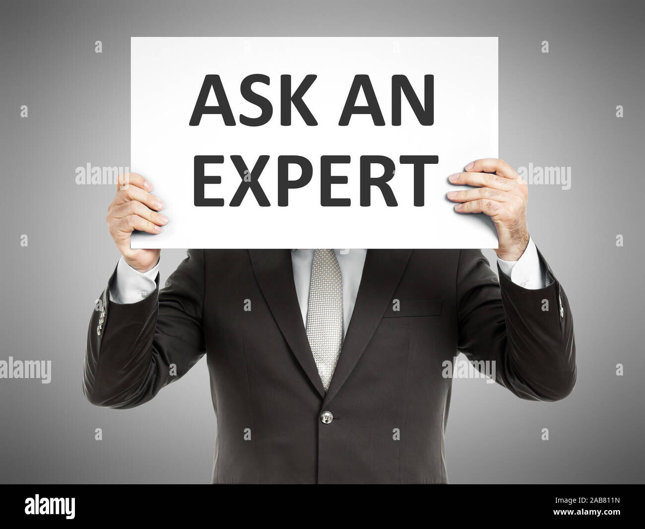 Ein Geschaeftsmann, der ein Schild mit den Worten 'Ask an Expert' in der Hand haelt Stock Photo