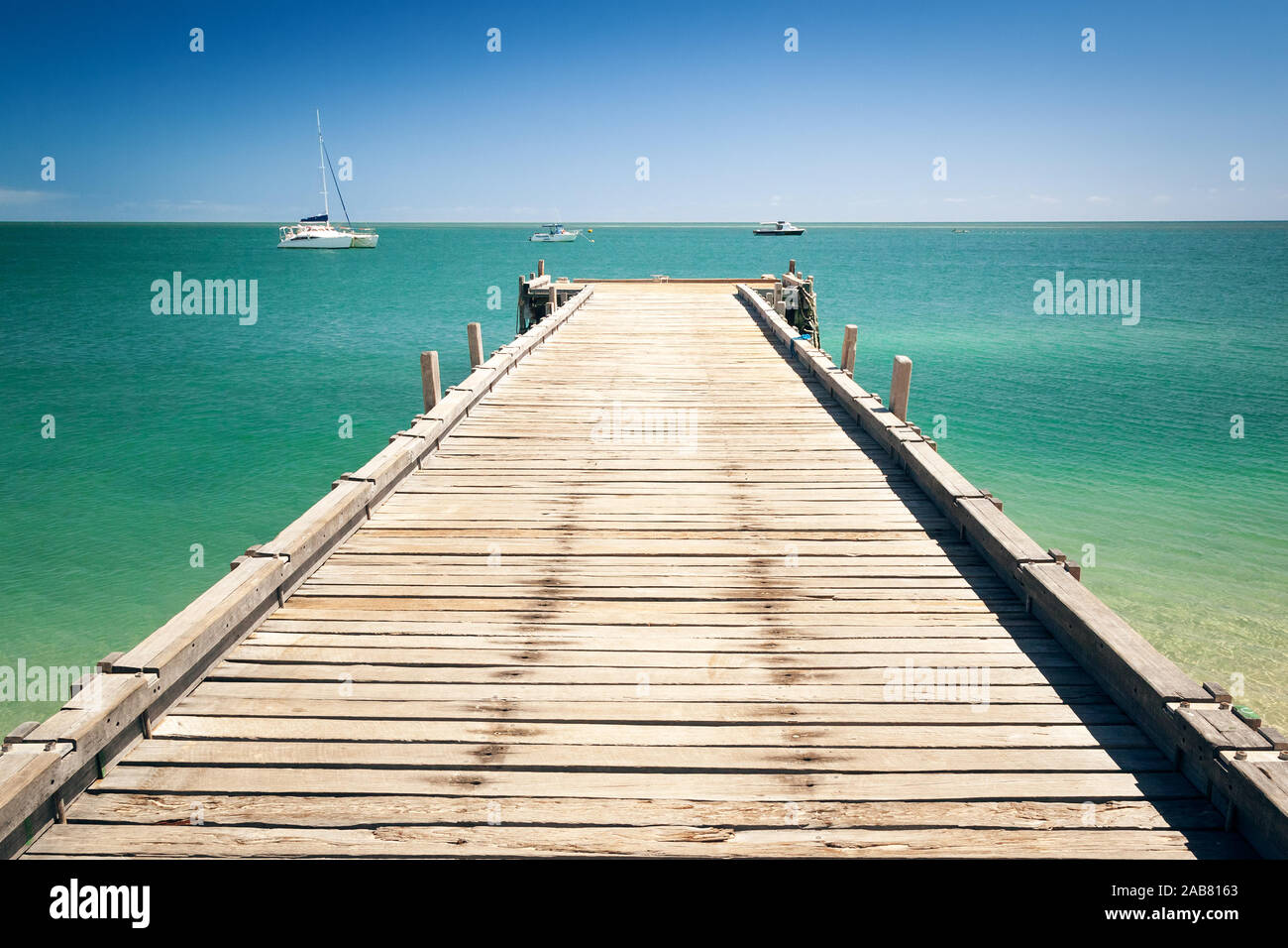 Ein schoener Bootssteg mit Blick auf den Ozean und Segelboote bei Monkey Mia in Australien Stock Photo