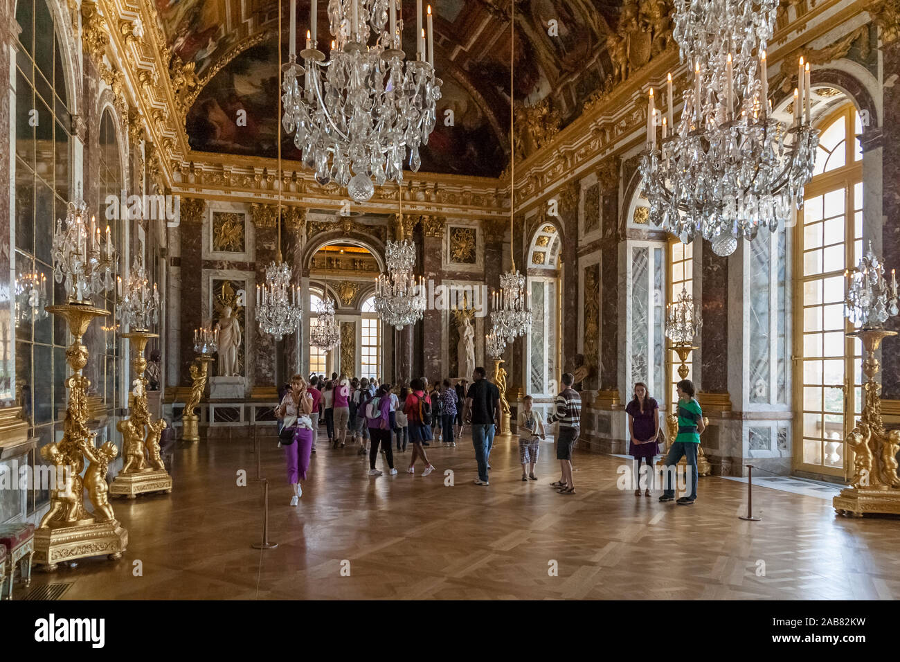 Great view of the beautiful Hall of Mirrors in the Palace of Versailles. Surrounded by crystal chandeliers and gilded sculptures, the remarkable... Stock Photo