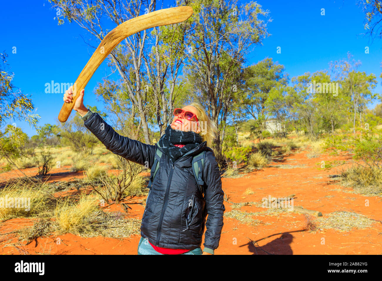 Happy tourist woman holding an aboriginal weapon of boomerang used by