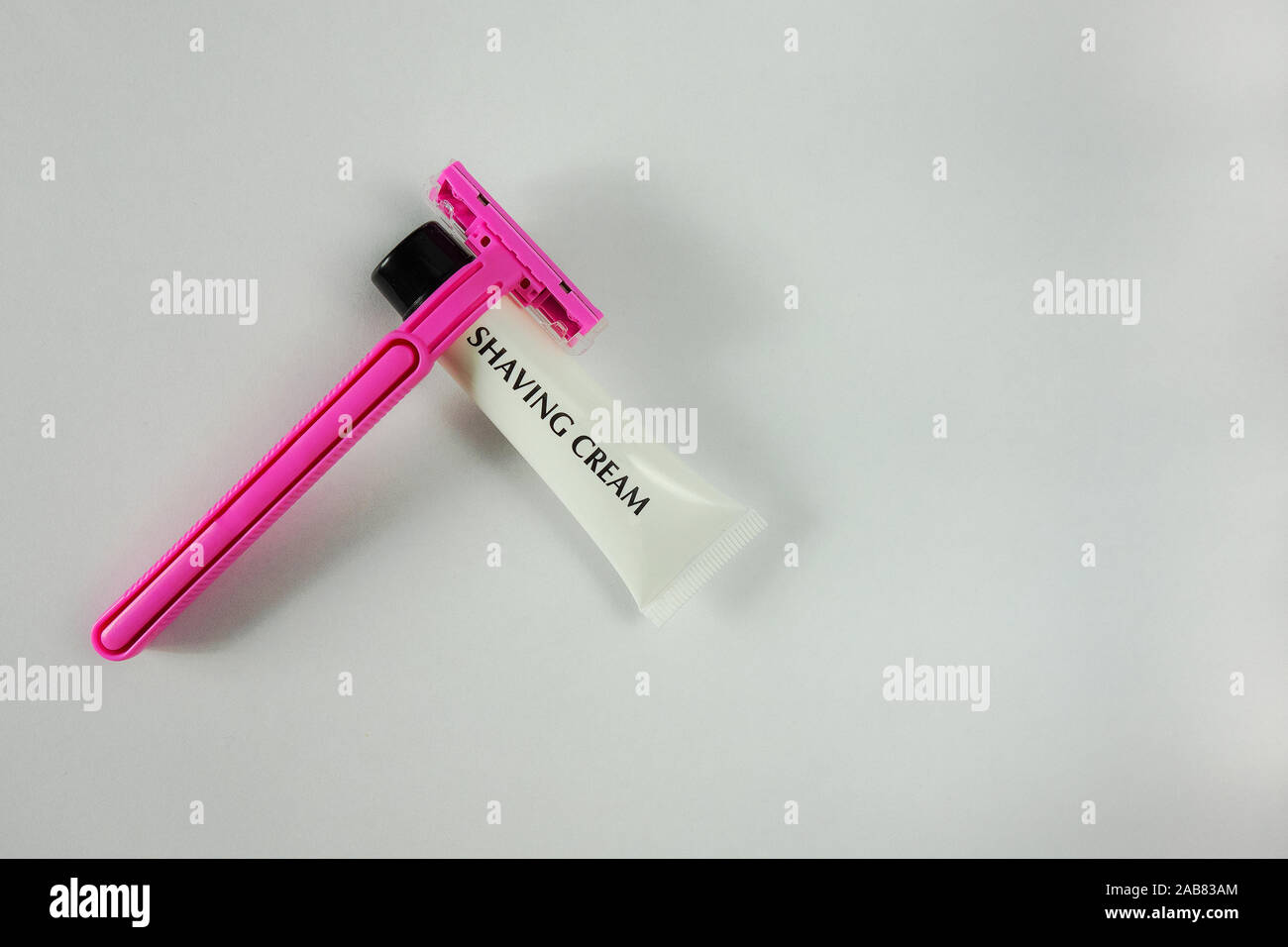 Pink shaving stick and white tube with shaving cream on light