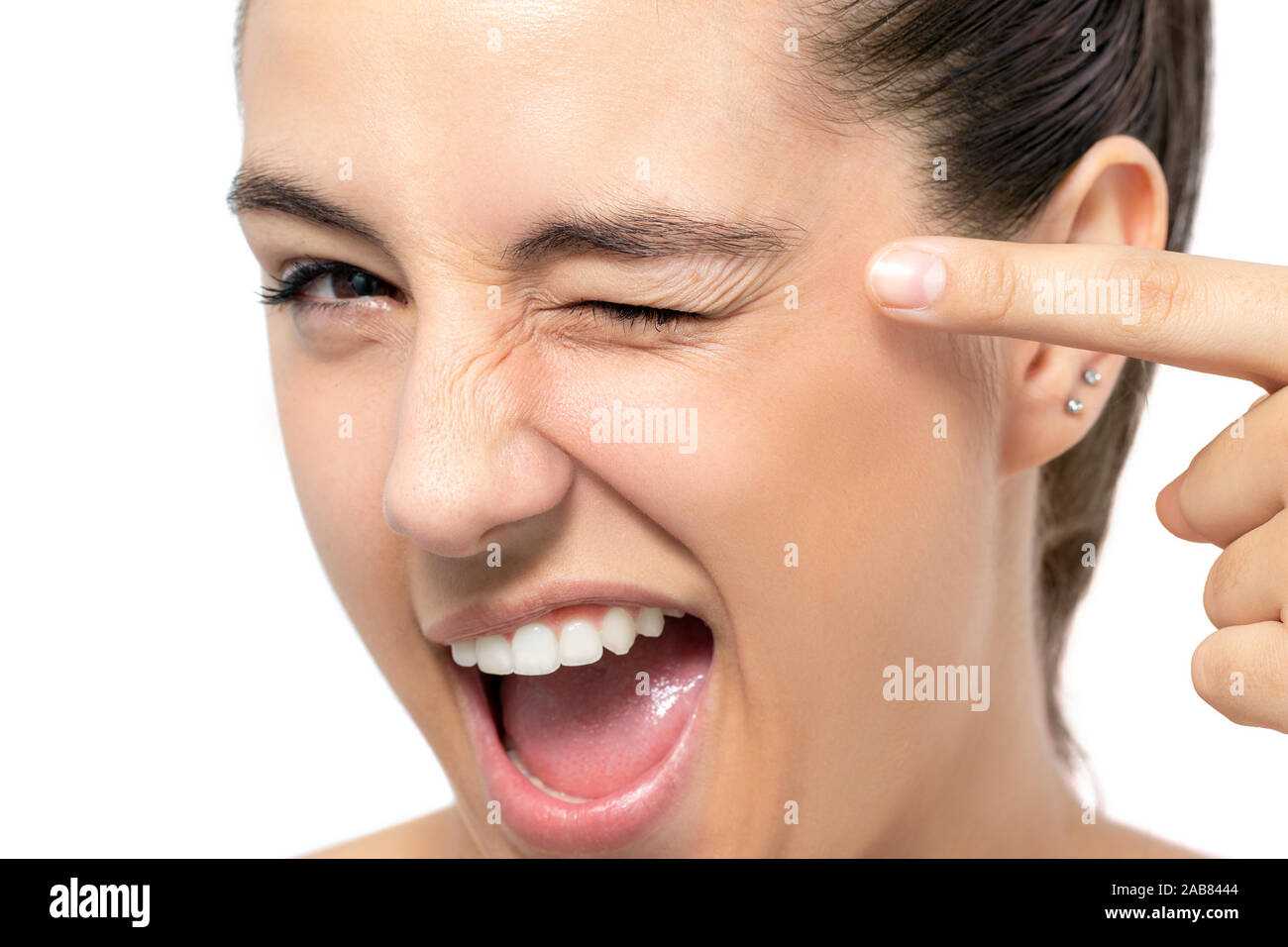 Close up fun portrait of woman pointing with finger at blinked eye.Isolated on white background. Stock Photo