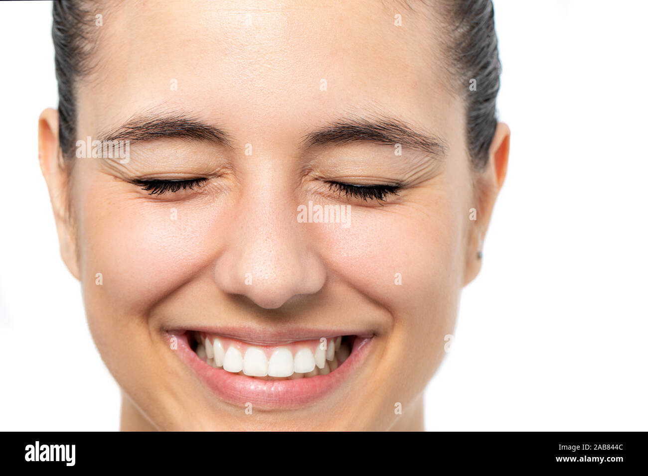 Close up face shot of woman with eyes closed tensing eyebrows. Isolated on white background. Stock Photo