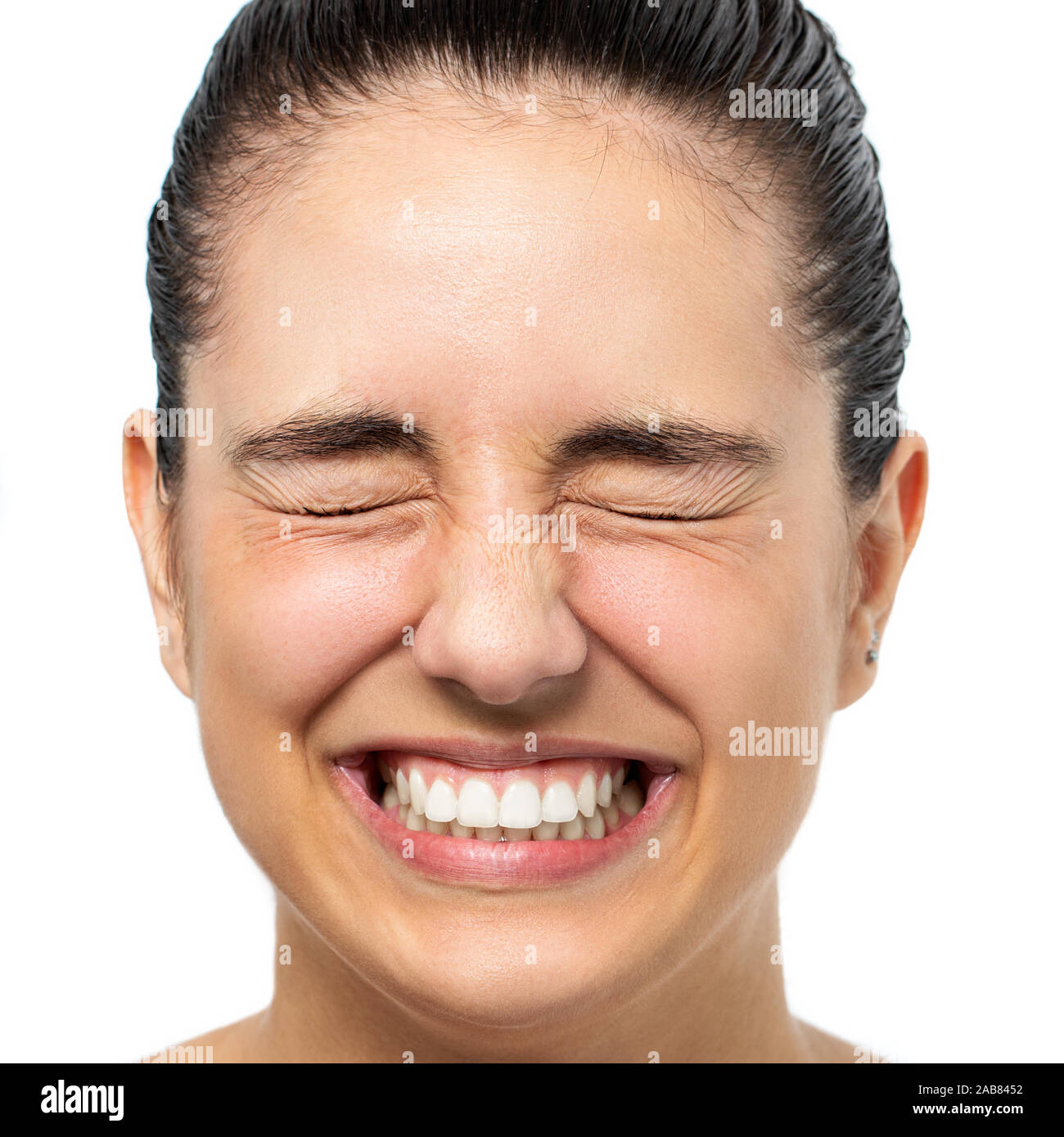 Close up face shot of young woman with eyes closed tensing eyes. Happy laughing girl isolated on white background. Stock Photo