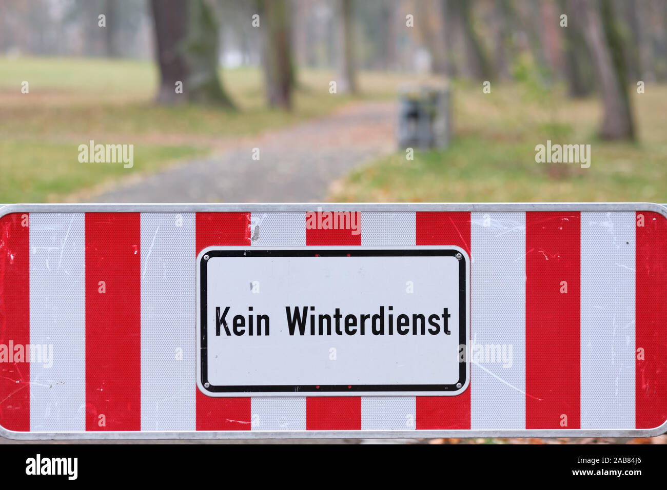 A red and white sign on a footpath at the entrance of a park in Nuremberg informs ' Kein Winterdienst ' (in Englisch: no winter service ). Seen in Fra Stock Photo