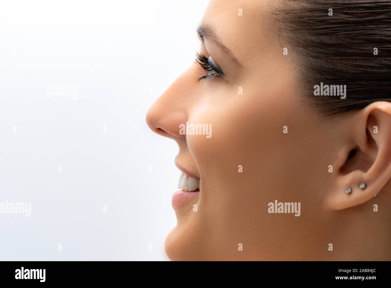 Macro close up portrait of beautiful young woman smiling. Girl looking aside isolated on white background. Stock Photo