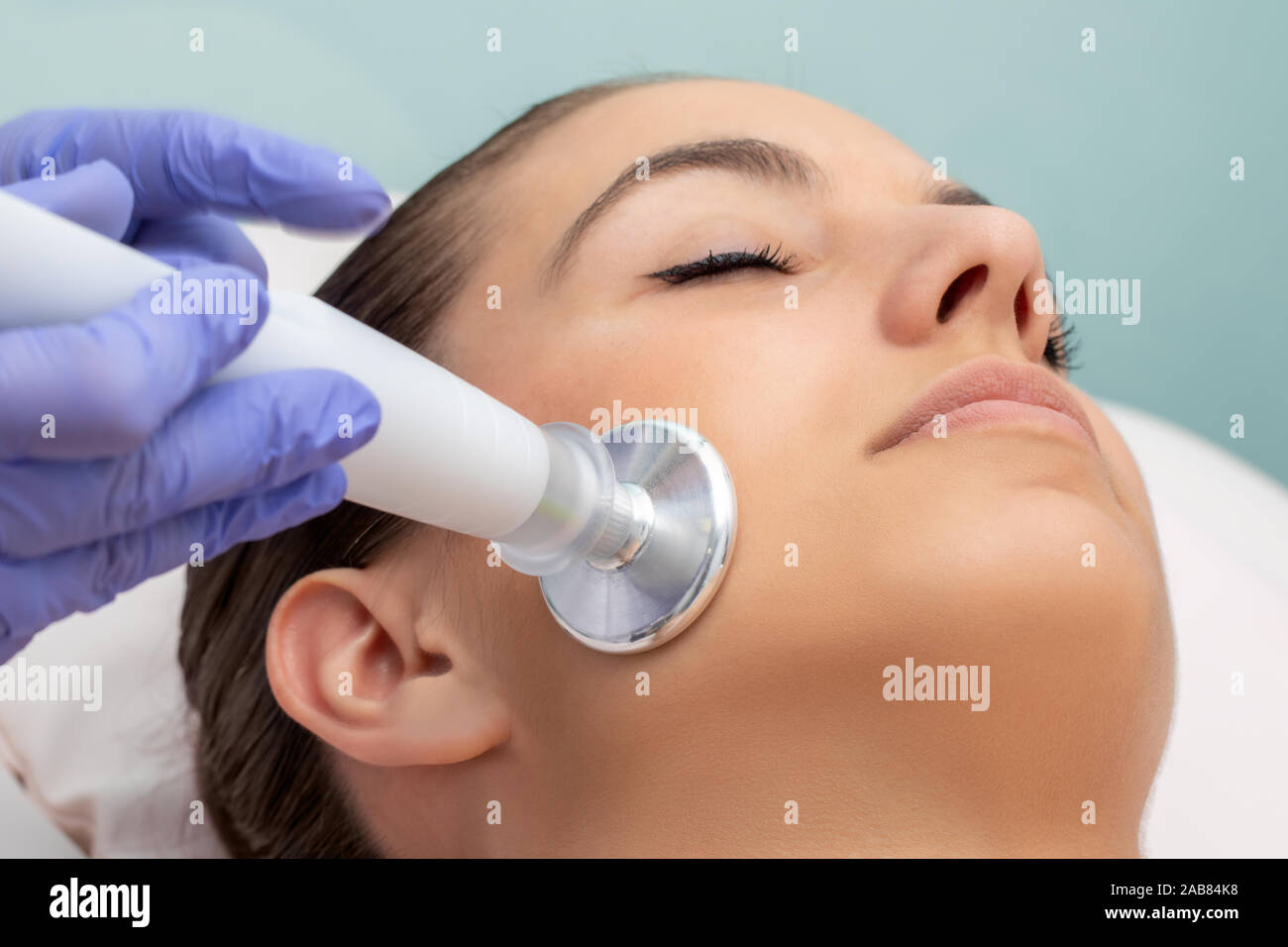 Macro close up of woman having facial mesotherapy. Therapist applying flat head plasma pen on side of face. Stock Photo