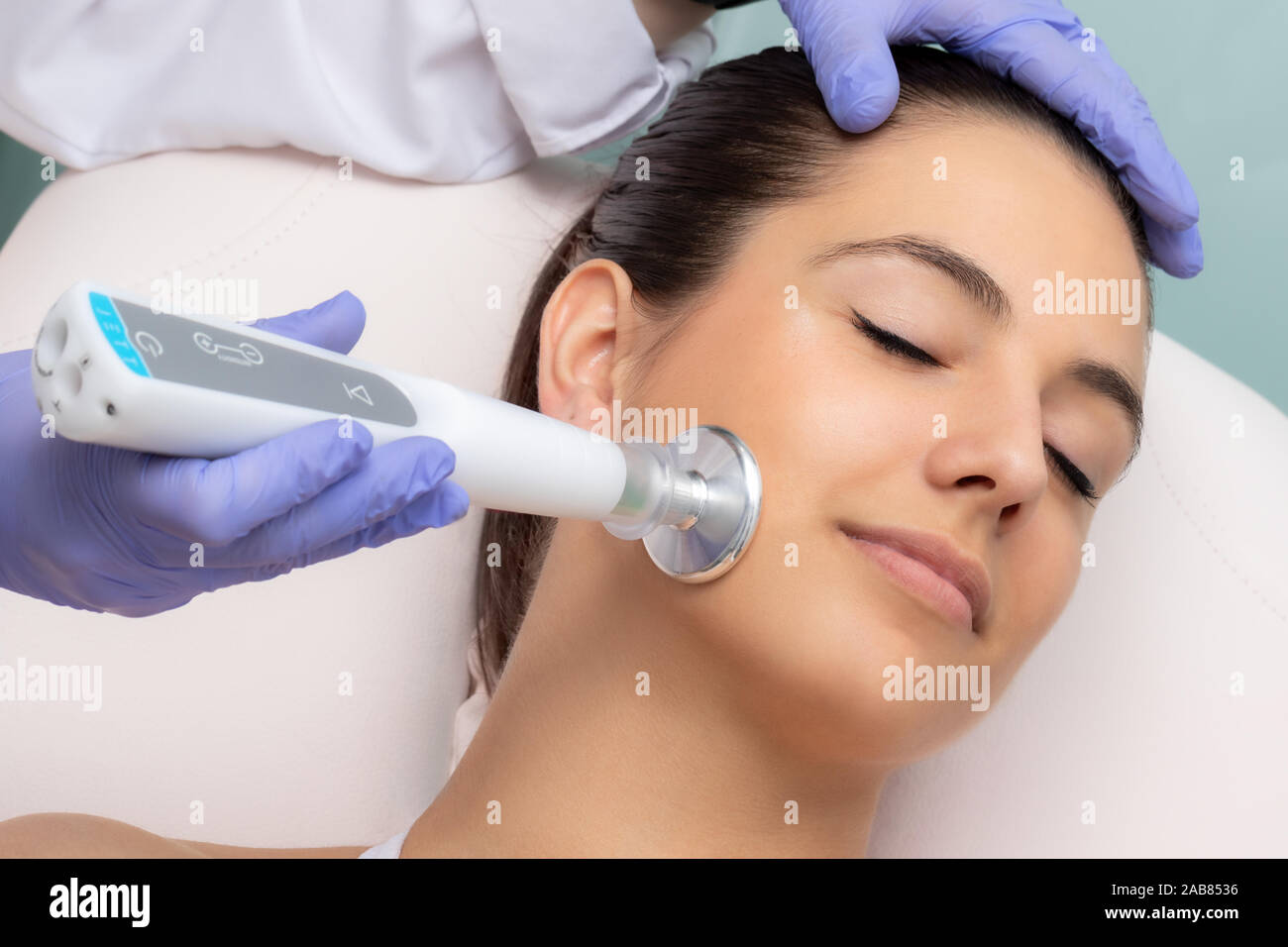 Close up of therapist doing facial mesotherapy treatment with flat head plasma pen. Electric impulse on woman's cheek stimulating new collagen. Stock Photo