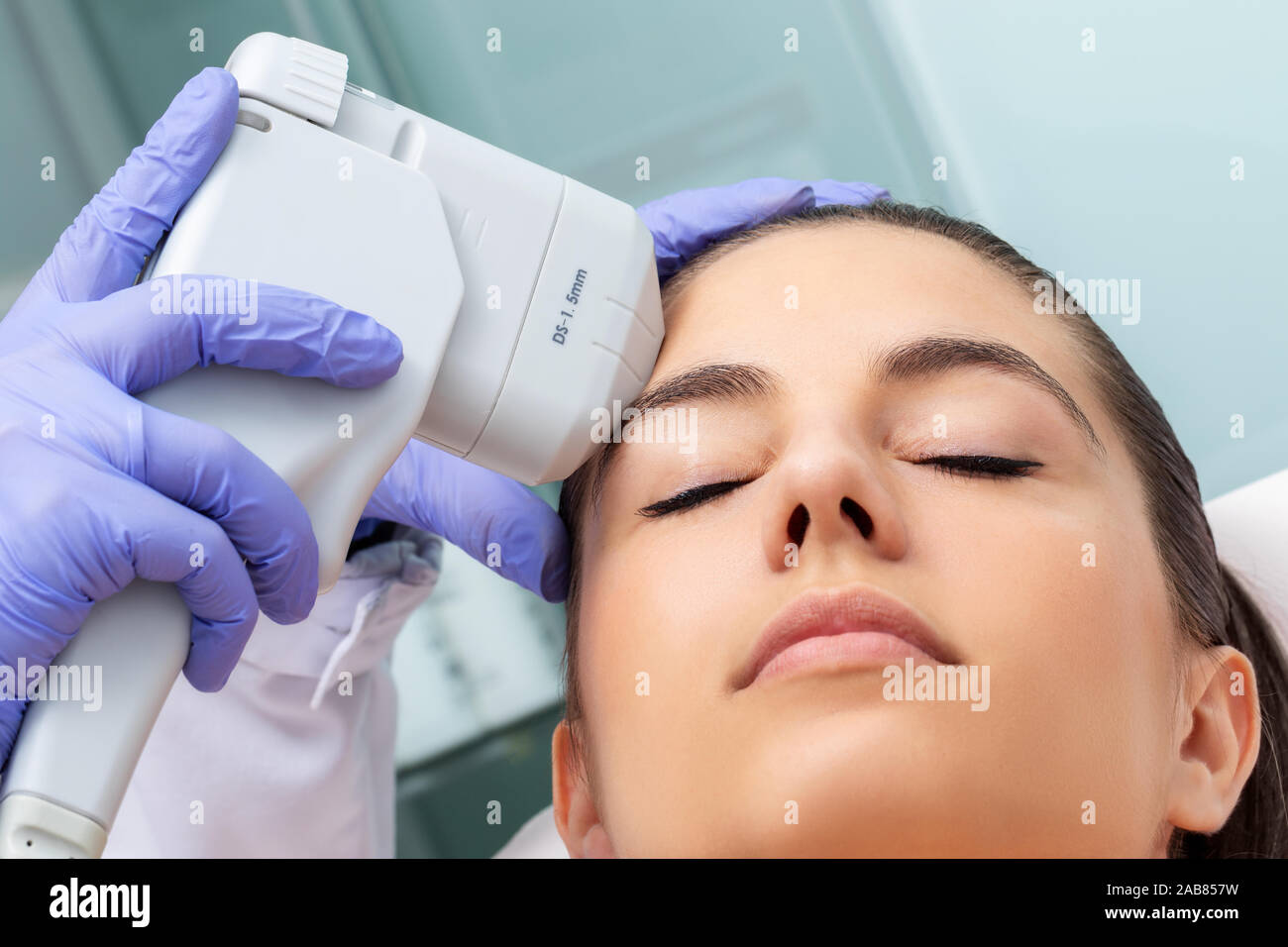 Close up of therapist doing removing sun damage on woman's forehead with high intensity ultrasound device. Stock Photo