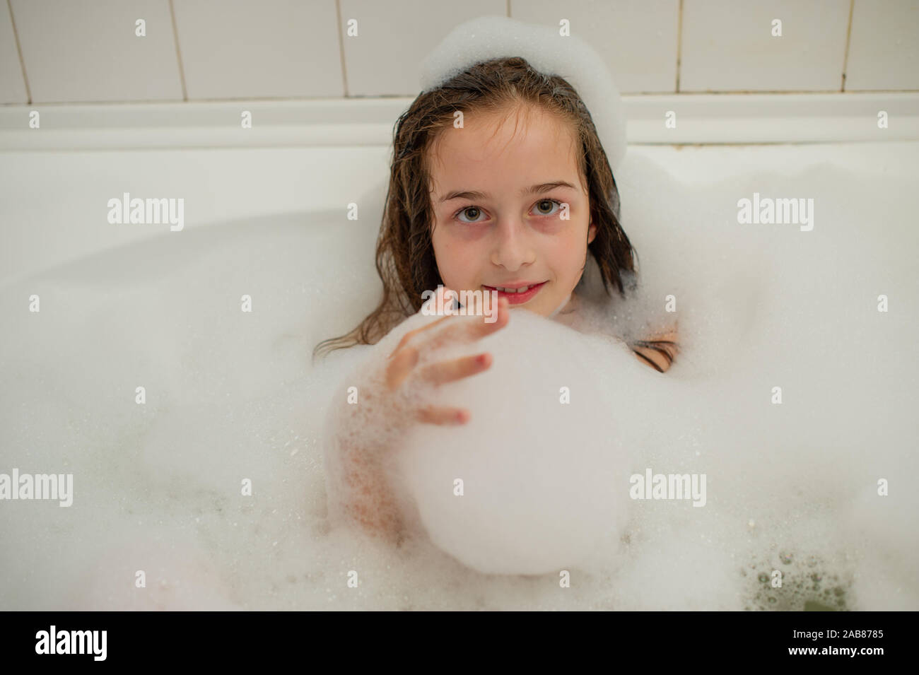 Young girl inside the bath. A little girl bathes in a bathtub with foam