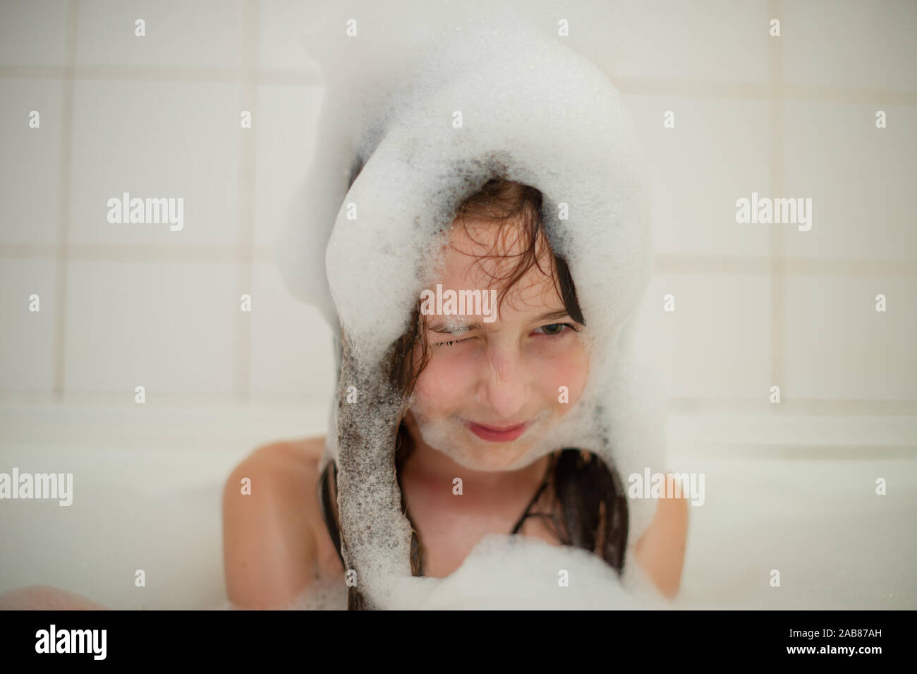 Young girl inside the bath. A little girl bathes in a bathtub with foam
