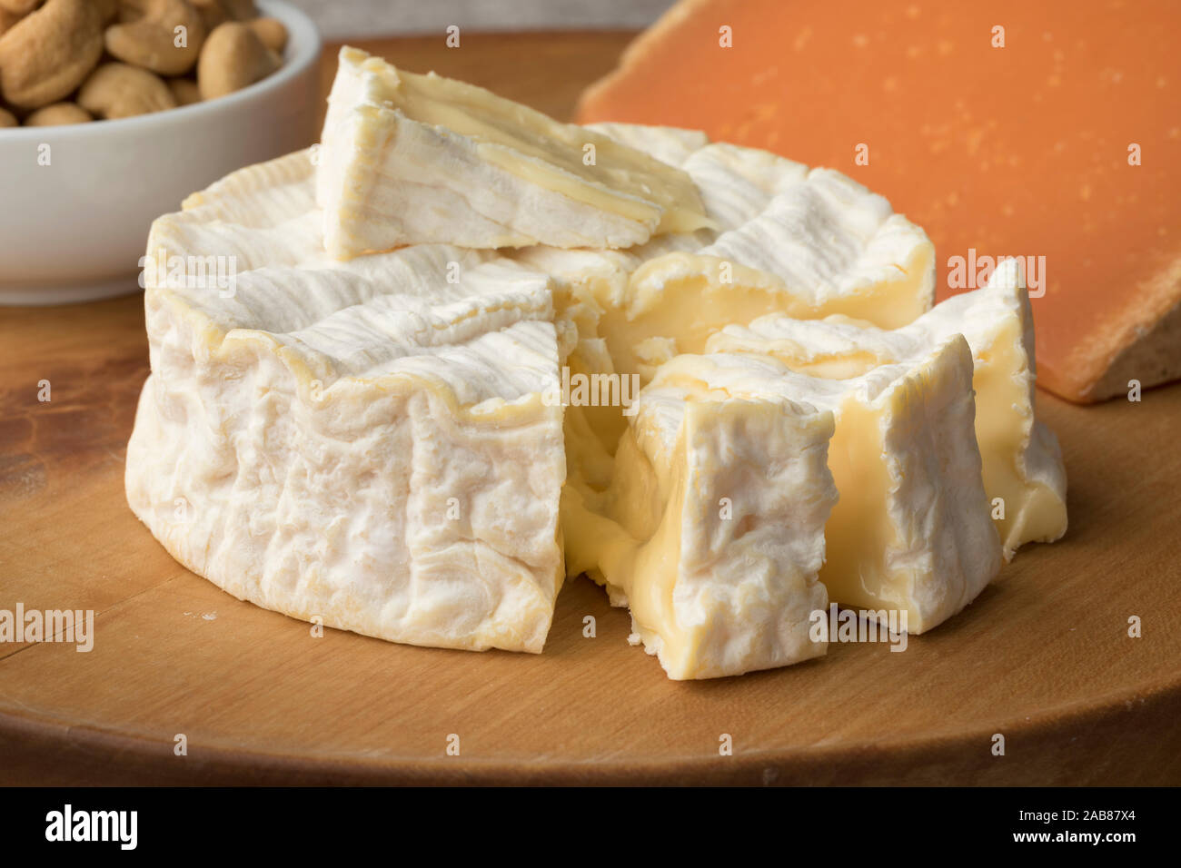 Traditional soft  French Camembert cheese and pieces close up on a cutting board Stock Photo