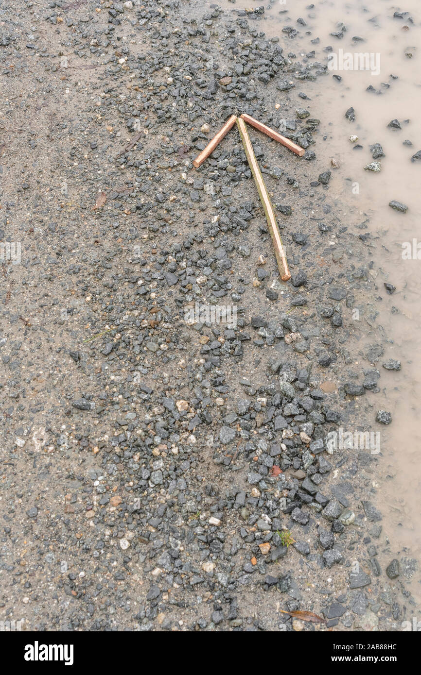 Survival skills concept. Signal arrow on gravel 'proceed this way' / 'proceeding in this direction' to show direction of movement or position. Stock Photo