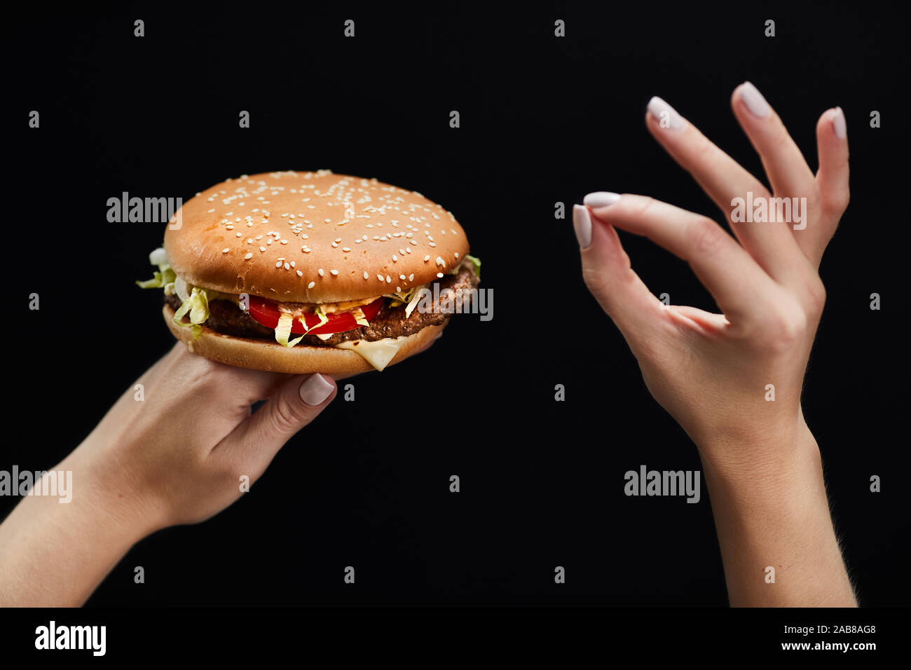 Woman Hands holding a hamburger and showing ok-sign Stock Photo