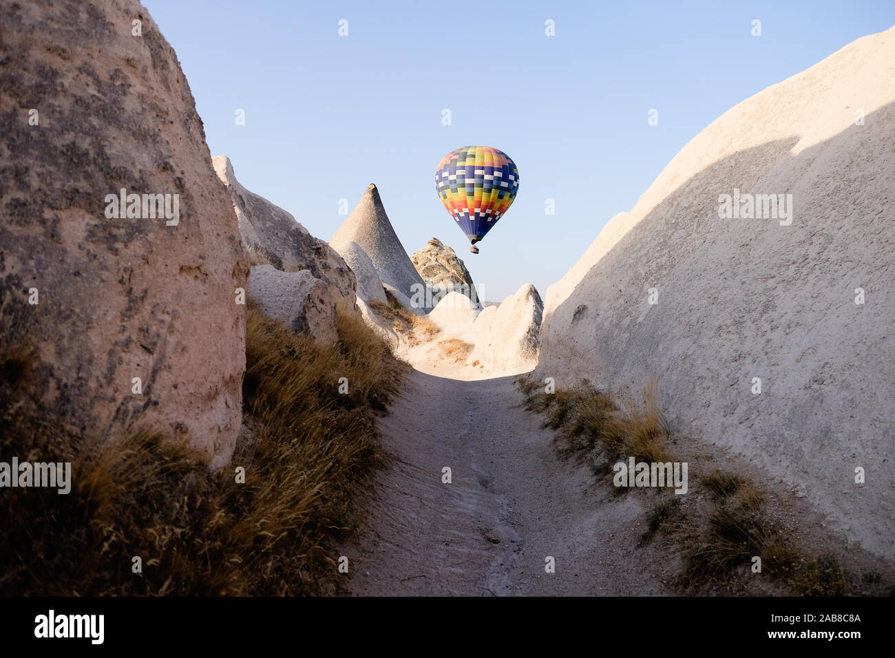 Single hot air balloon framed by rocks on a walking path Stock Photo