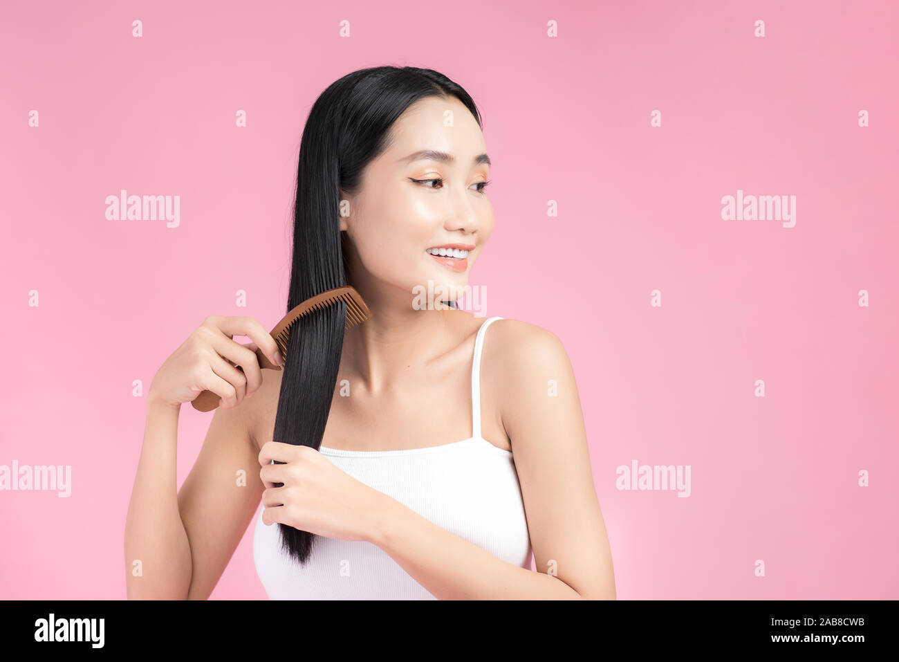 Close up portrait of happy satisfied beautiful girl while combing her hair Stock Photo