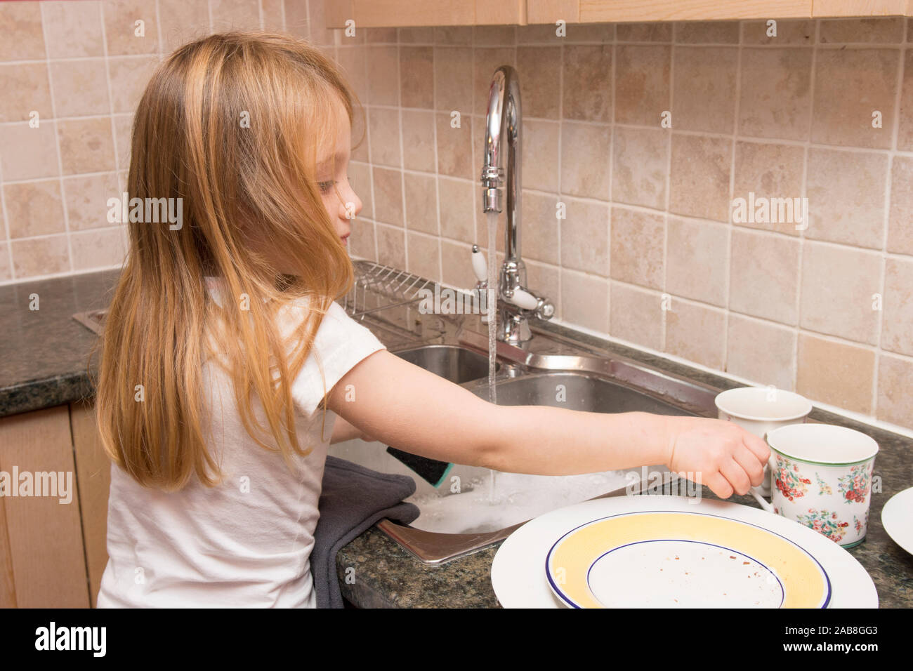 young child washing up at kitchen sink, home chores Stock Photo