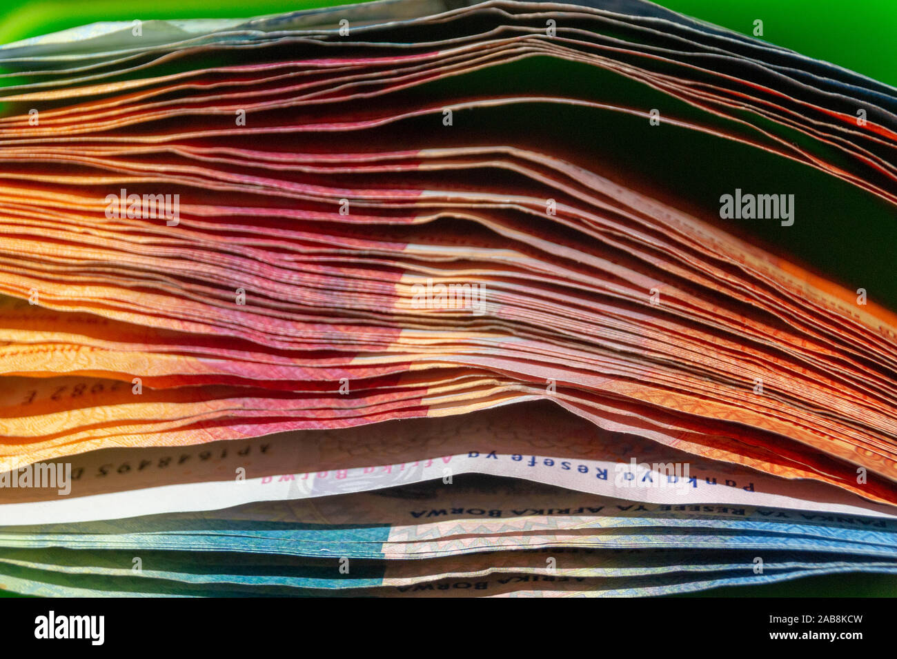 A close up side view of a pile of one and two hundred rand notes Stock Photo